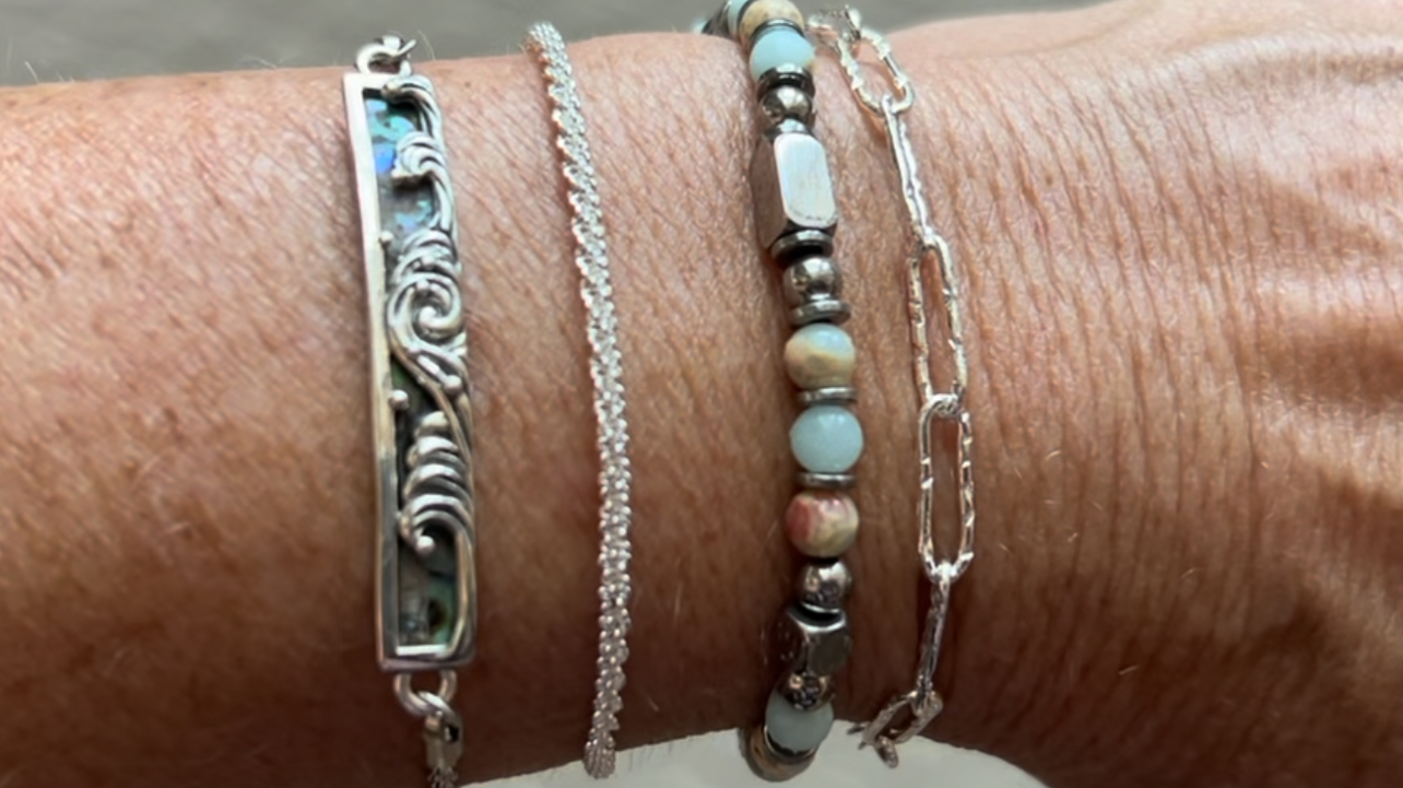Stacked boho style bangle bracelets in mixed sizes and colors on a woman’s wrist