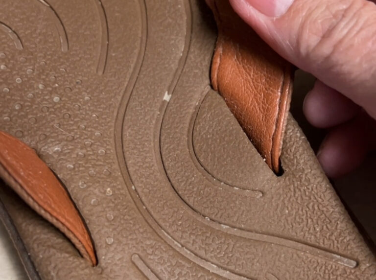 Women’s non slip flip flops on a pool deck next to a towel and sunglasses