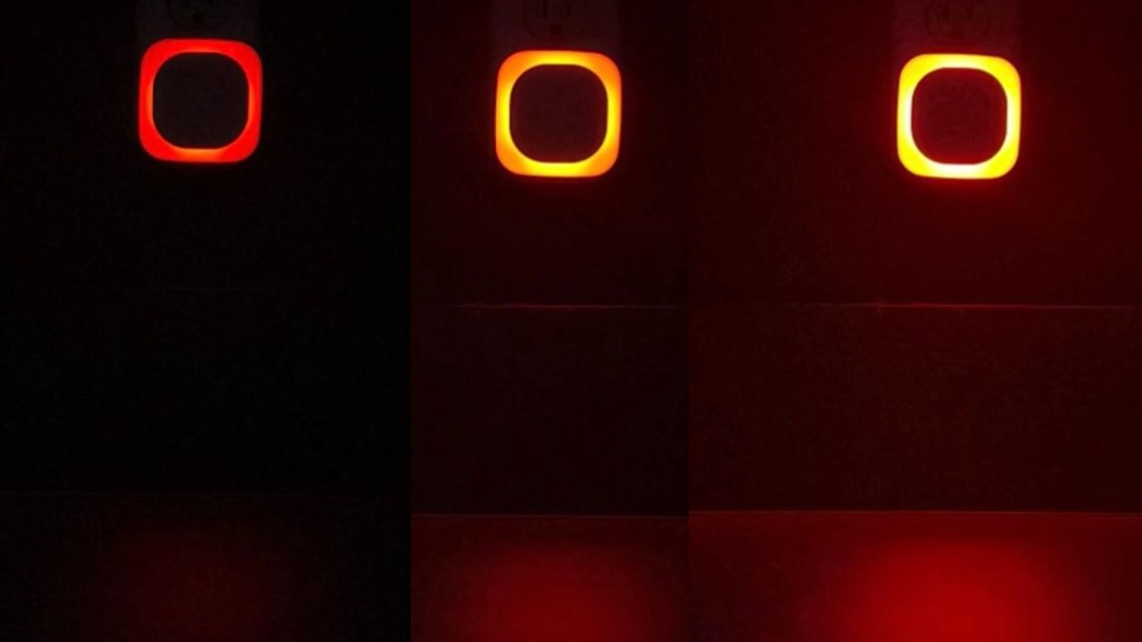 Dimmable red night light glowing softly on a bedroom wall near a nightstand