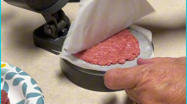 Metal burger press with wax paper insert shaping ground beef into even patties
