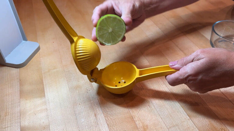 Sturdy handheld lemon squeezer pressing juice into a bowl.