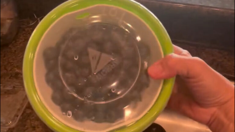 Berry colander with fresh fruit sitting in matching serving bowl.