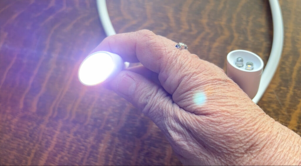 Lumos knitting light with bendable arms shining on knitting needles.