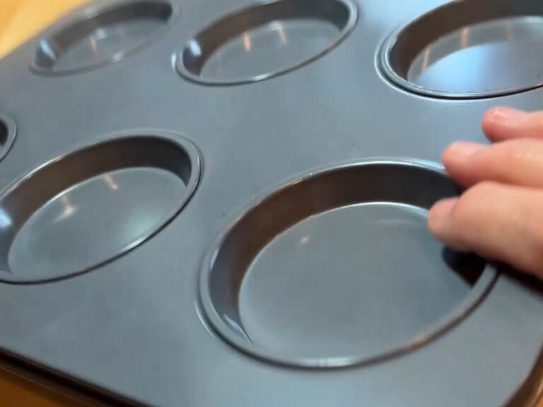 Muffin top pan with six shallow wells filled with batter.