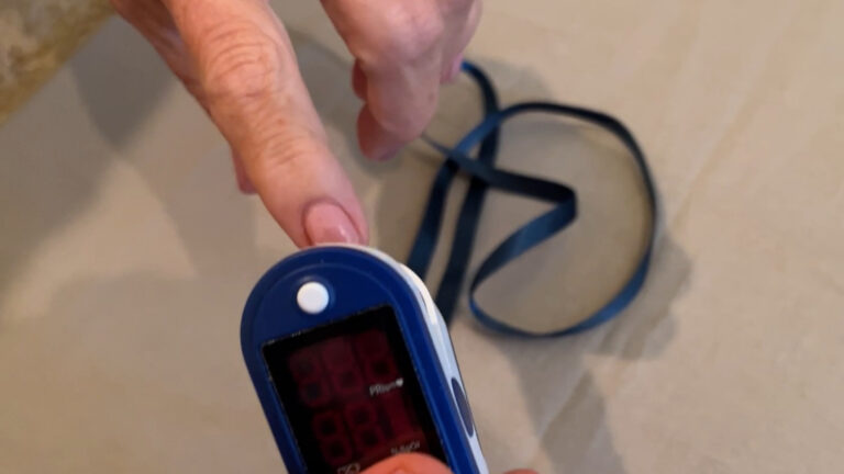 Finger pulse oximeter clipped on finger showing oxygen and heart rate results.