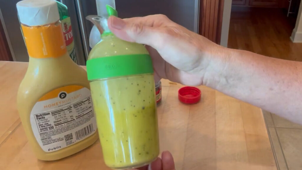 Salad dressing shaker with measurement markings filled with oil and vinegar.