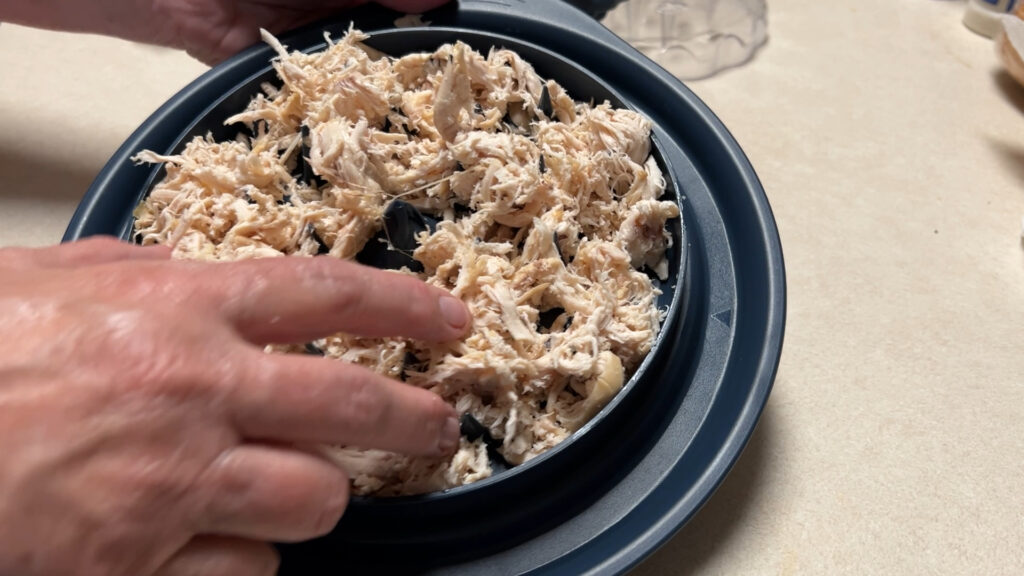 Chicken shredder gadget with spiked base and lid for shredding meat quickly.