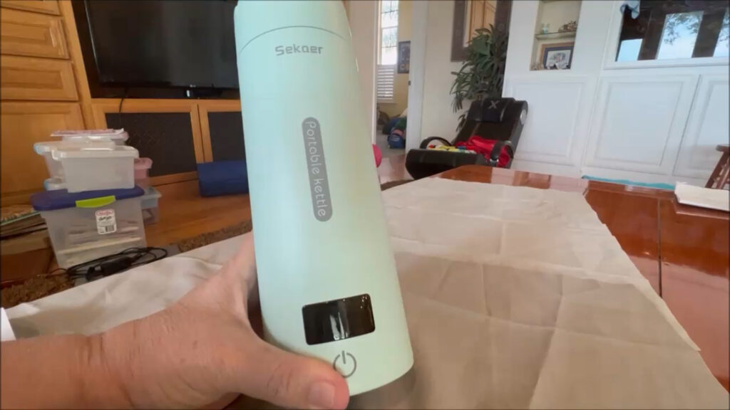 Portable travel electric tea kettle with buttons and travel case.