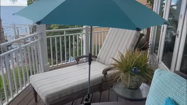 Adjustable clamp umbrella providing shade on a chair outdoors.