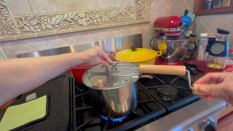 Whirley-Pop popcorn maker on stovetop popping fresh popcorn.