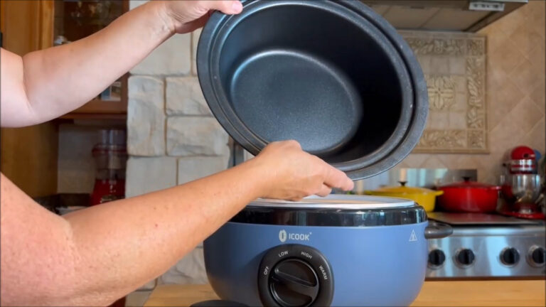 Blue aluminum slow cooker with glass lid on kitchen counter.