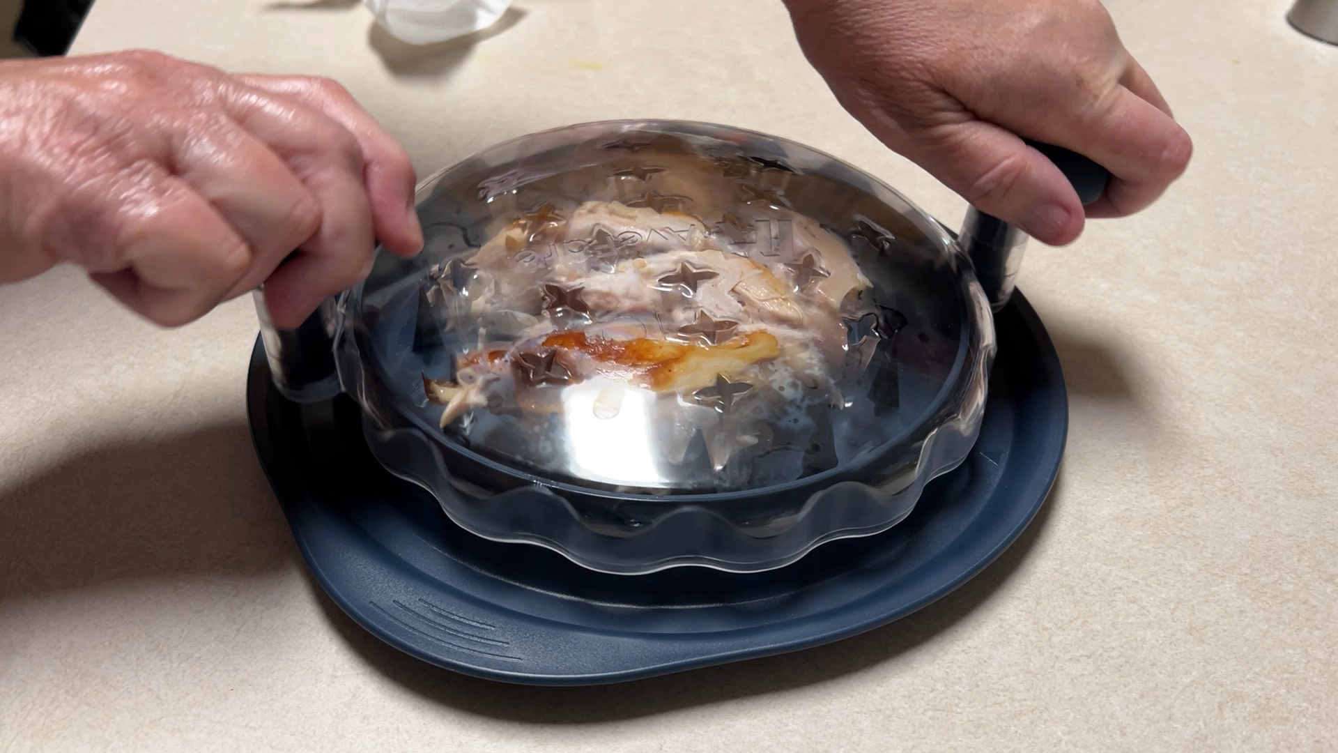 hands using a chicken shredder tool in the kitchen